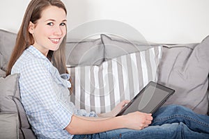 Woman sitting on couch and uses tablet device