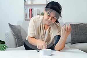 A woman is sitting on a couch and using a blood pressure monitor
