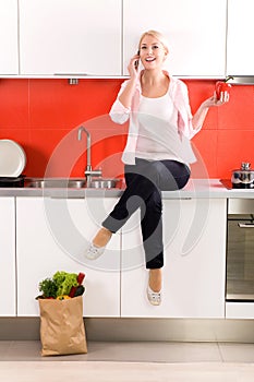 Woman sitting on counter in kitchen