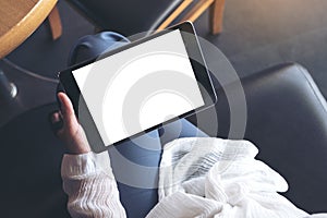 A woman sitting cross legged and holding black tablet pc with blank white desktop screen