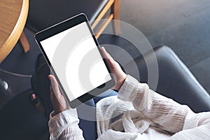 A woman sitting cross legged and holding black tablet pc with blank white desktop screen