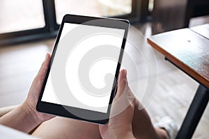 A woman sitting cross legged and holding black tablet pc with blank white desktop screen