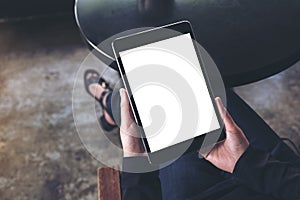 A woman sitting cross legged and holding black tablet pc with blank white desktop screen