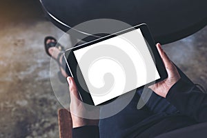 A woman sitting cross legged and holding black tablet pc with blank white desktop screen