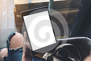 A woman sitting cross legged and holding black tablet pc with blank white desktop screen