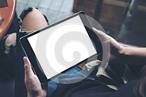 A woman sitting cross legged and holding black tablet pc with blank white desktop screen