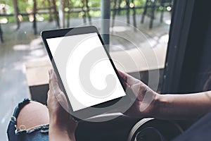 A woman sitting cross legged and holding black tablet pc with blank white desktop screen