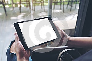 A woman sitting cross legged and holding black tablet pc with blank white desktop screen