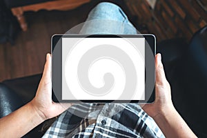 A woman sitting cross legged and holding black tablet pc with blank white desktop screen