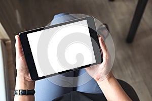 A woman sitting cross legged and holding black tablet pc with blank white desktop screen in office