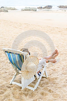 Woman sitting on a deck chair relaxing at the beach