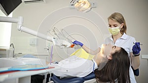 A woman is sitting in a dental chair while a dentist examines her teeth