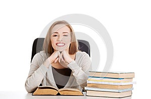 Woman sitting at the desk full of books