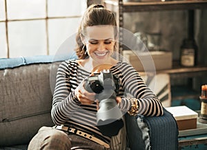 Woman sitting on divan and using dslr photo camera