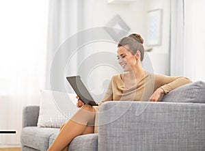 Woman sitting on divan and using tablet pc