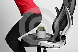 Woman sitting down into armchair with cactus on background, closeup. Hemorrhoids concept photo