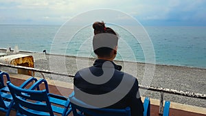 Woman sitting on empty beach seaside, relaxing on vacation, loneliness, sadness