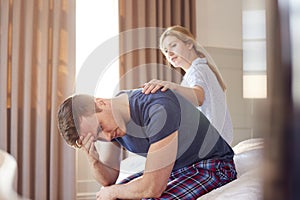 Woman Sitting On End Of Bed At Home Comforting Man Suffering With Mental Health Issues photo