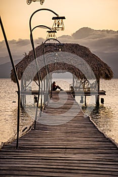 Woman sitting enjoying a beautiful sunset from a wooden dock