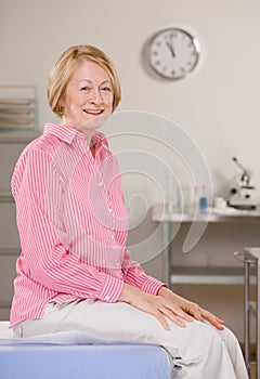 Woman sitting on exam table during checkup photo