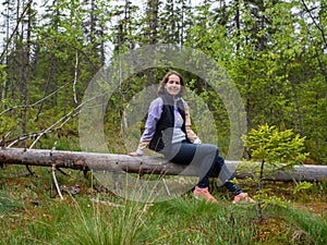 woman sitting on fallen tree in a green forest