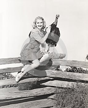 Woman sitting on fence petting her turkey