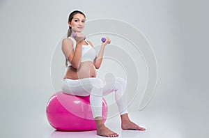 Woman sitting on a fitness ball and workout with dumbbells