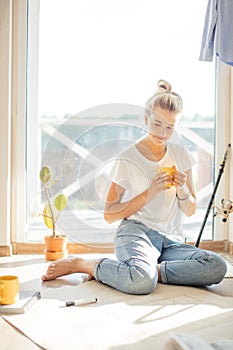 Woman sitting on floor of new house planning home on paper.