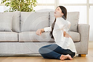 Woman sitting on floor touching her back