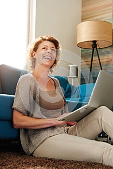 Woman sitting on floor typing on laptop laughing