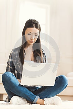 Woman sitting on floor and working on laptop