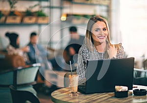 Woman sitting in front of open laptop computer in cafe