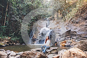 A woman sitting in front of waterfall in the jungle