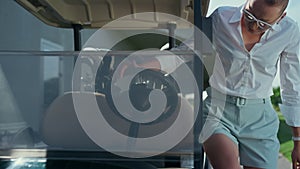 Woman sitting golf cart on sunny day. Professional player start engine on course