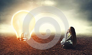 Woman is sitting on a ground and looking at lamp