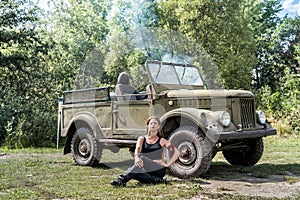 Woman sitting on the ground near military car