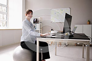 Woman Sitting On Gym Ball In Office