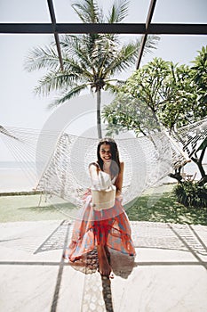 Woman sitting in a hammock by the beach