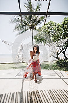 Woman sitting in a hammock by the beach