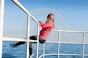 Woman sitting on handrail by the sea