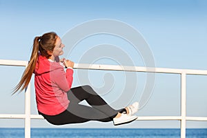 Woman sitting on handrail by the sea