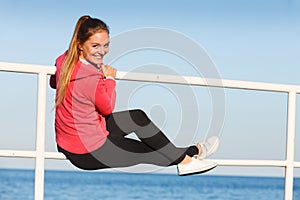 Woman sitting on handrail by the sea