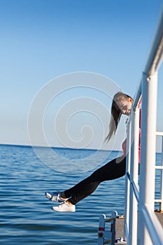 Woman sitting on handrail by the sea