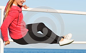 Woman sitting on handrail by the sea