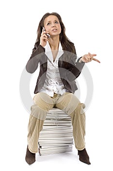 Woman sitting on the heap of files, talking mobile phone