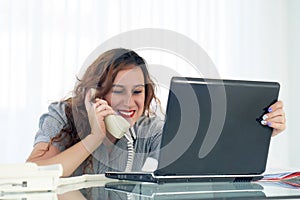 Woman sitting at her desk working and answering a phone call