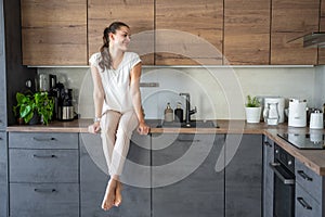 Woman sitting on her kitchen counter at home