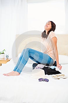 Woman sitting on her overfull suitcase