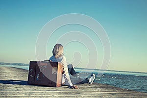 woman sitting on her suitcase waiting for the sunset in a spectacular view