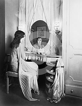 Woman sitting at her vanity table smiling into the mirror